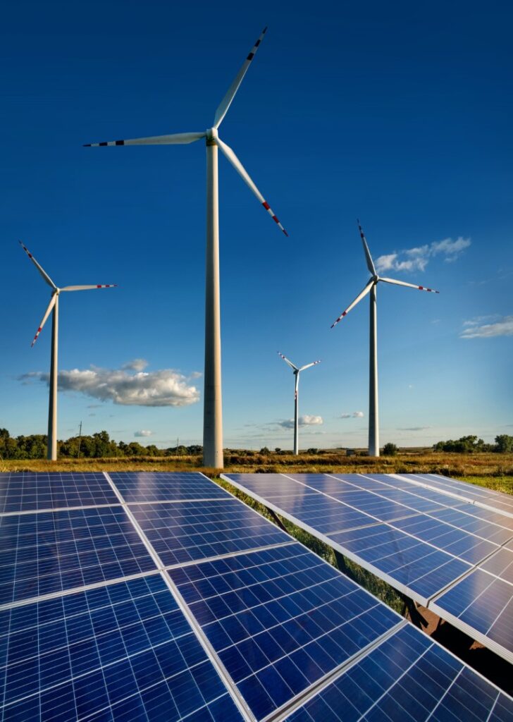 Solar panels in the foreground with wind turbines in the background